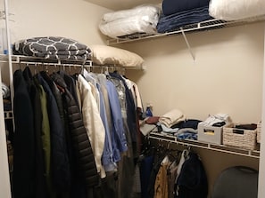 Ein Schrank mit Kleiderstangen, Regalen für gefaltete Wäsche und Aufbewahrungsboxen.