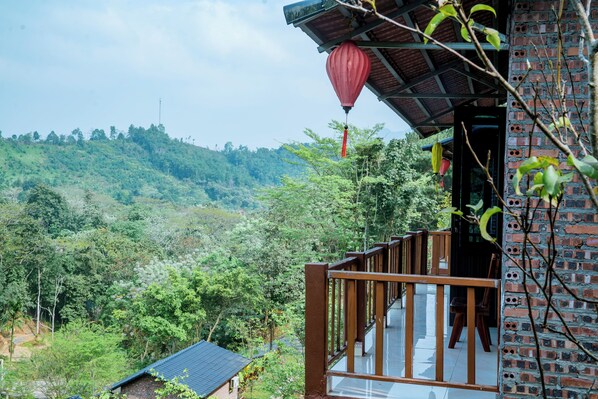 A wooden balcony with a view of a lush green hillside. - Lùng Càng Farmstay (Ha Giang 2)