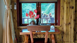 Une table en bois avec une chaise devant une fenêtre donnant sur un paysage verdoyant.