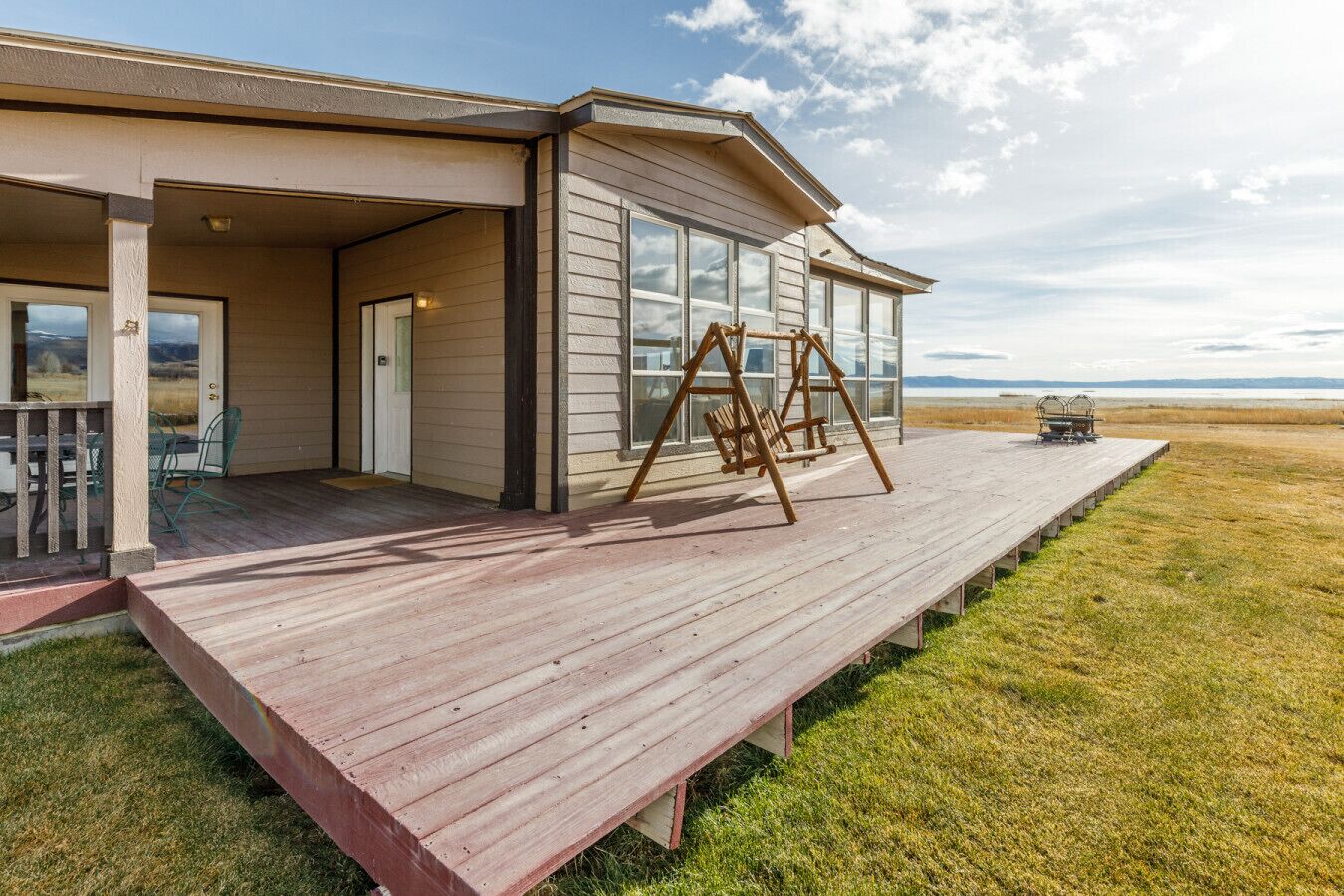 A modern house with a covered porch, a swing set, and a view of the landscape.