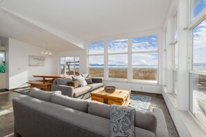A spacious living room with a large window, a sofa, a coffee table, and a dining area. - Lakefront Retreat; An Unmatched Private Escape With Acres of Seclusion! (Saint Charles)