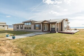 A single-story house with a front porch, large windows, and a view of the beach.