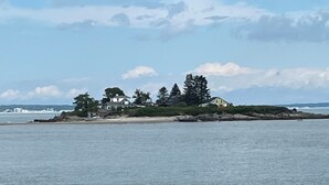Un paysage côtier avec des rivages rocheux, une petite île couverte d’arbres et un ciel dégagé.