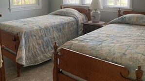 Une chambre à coucher avec deux lits en bois, une table de chevet, une lampe et une fenêtre avec des rideaux.