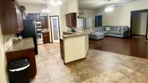 A spacious living area with a kitchen, a dining area, and a seating area with a sofa. - Lawton Lonesome Dove 4 Bd/3 Ba Home (Lawton)