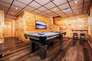 A pool table in a wooden room with a television on the wall and a fire extinguisher. - Fiddler's Friend - Hot Tub Soaks, Theater Movie Nights & Game Room Competitions (Pigeon Forge)