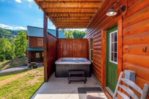A log cabin with a hot tub, a covered porch, and a view of the surrounding landscape. - Fiddler's Friend - Hot Tub Soaks, Theater Movie Nights & Game Room Competitions (Pigeon Forge)