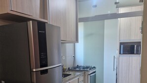 Cozinha equipada com geladeira, fogão, micro-ondas e painel de azulejos.