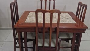 Mesa de jantar com quatro cadeiras, um interruptor de luz e uma tomada na parede.