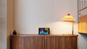 Et trækonsolbord med en tablet, en lampe og en lille vase med rør.