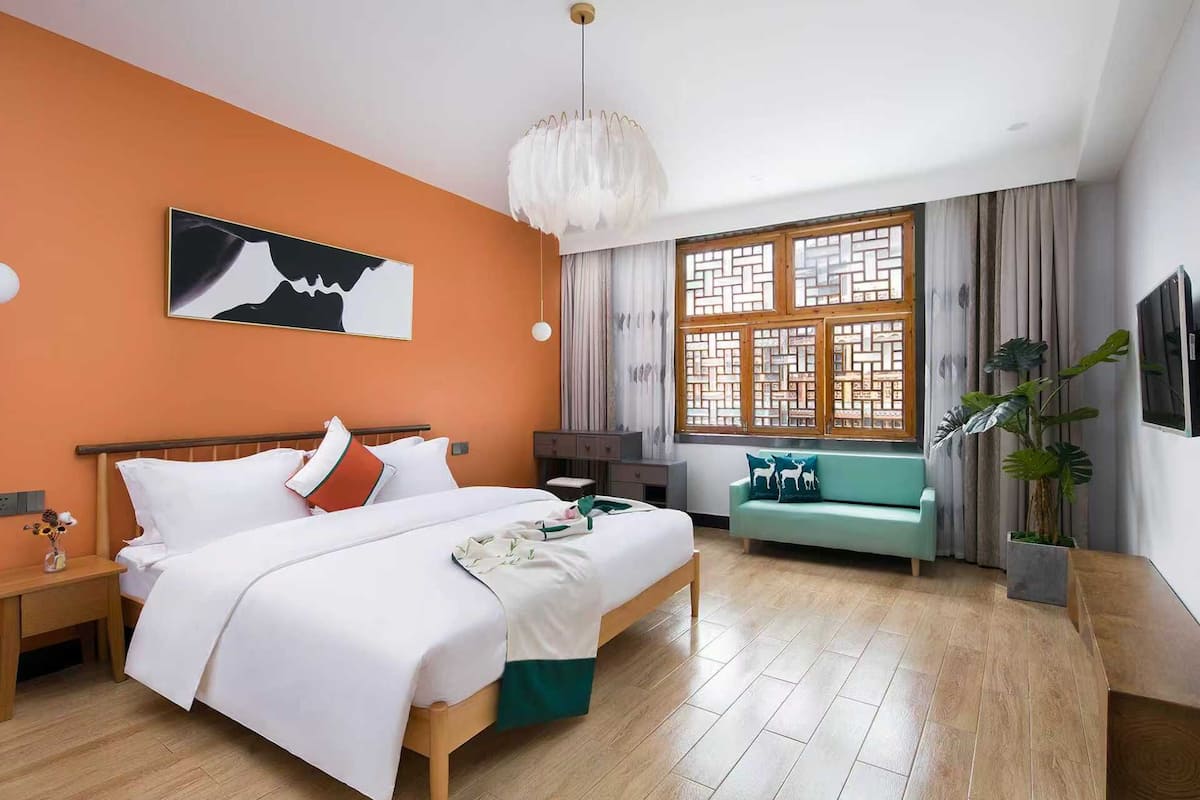 Habitación de hotel con cama, escritorio, silla, televisor y ventana con vistas.