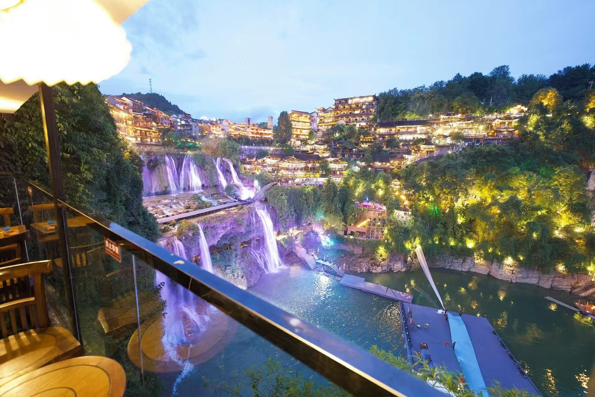 Vista de un pueblo a orillas del río con varias cascadas, un puente y edificios tradicionales.