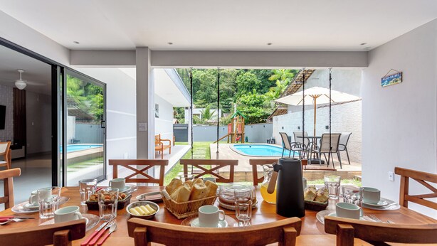 A dining area with a table set for breakfast, a pool, and a view of the garden.