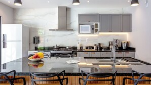 A modern kitchen with a marble countertop, stainless steel appliances, and a central island with seating.