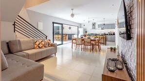 A modern living room with a sofa, dining table, and kitchen in the background.