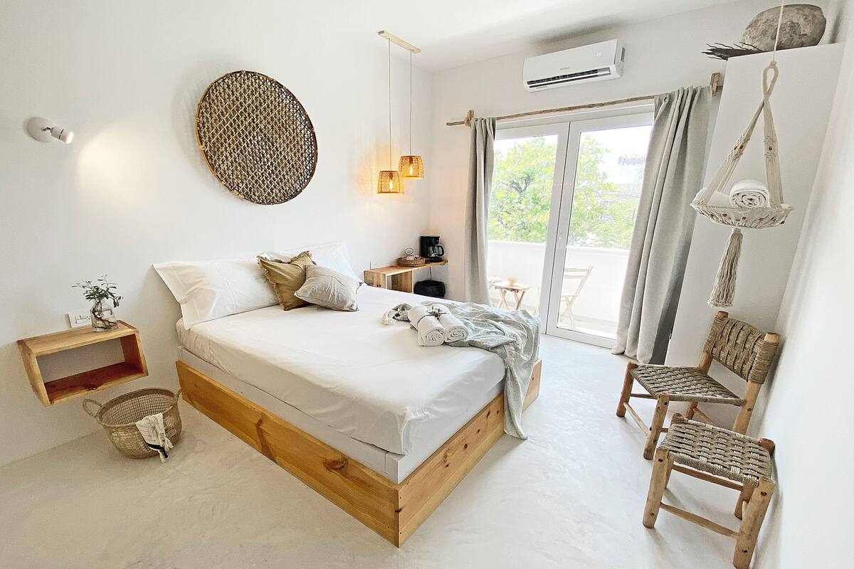 Une chambre à coucher avec un lit, une table de chevet, une chaise et une vue sur l’extérieur.