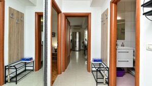 Un couloir avec des portes en bois, un réfrigérateur et un meuble blanc.