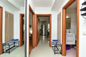 Un couloir avec des portes en bois, un réfrigérateur et un meuble blanc.