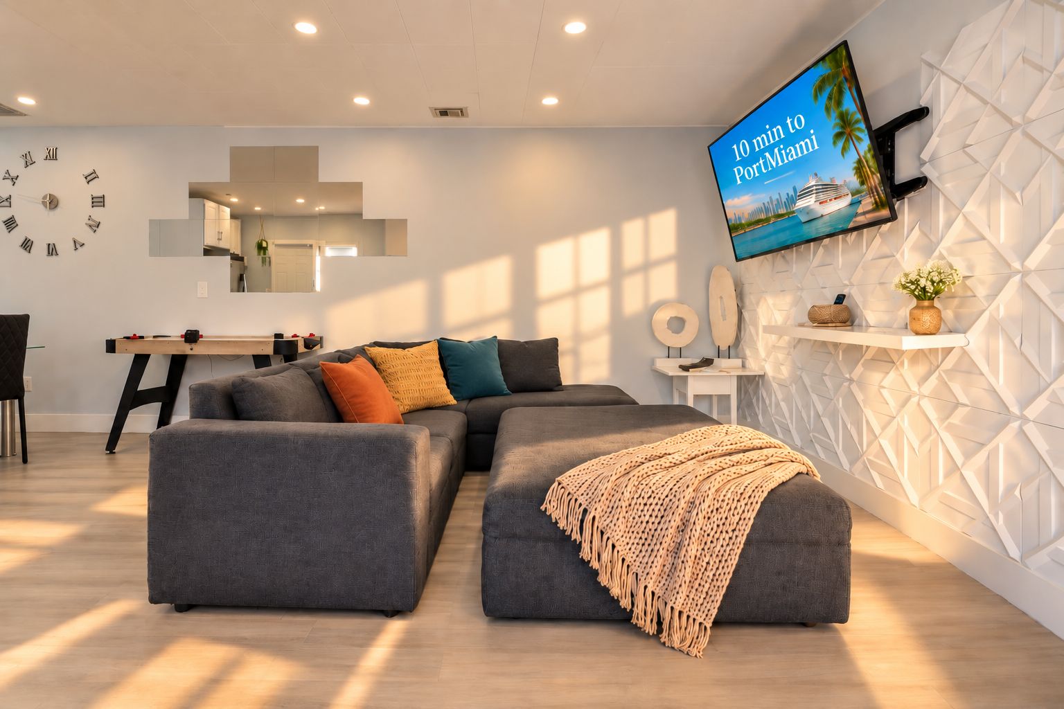A modern living room with a sectional sofa, a flat-screen TV, and a decorative wall.