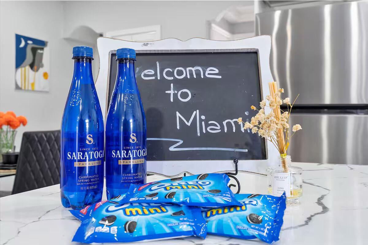 A welcome sign, two bottles of Saratoga sparkling water, and packets of Mini chocolate chips on a marble table.
