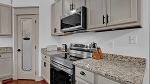 A kitchen with a microwave, oven, and granite countertop.