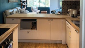 A modern kitchen with a central island, built-in appliances, and a view to the outside. - OP 63 - Rest & Recharge at Your Beachside Escape (Coffs Harbour)