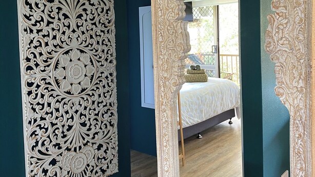 A bedroom with a bed, a large mirror, and a decorative wall panel. - OP 63 - Rest & Recharge at Your Beachside Escape (Coffs Harbour)