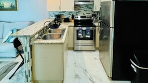 Een compacte keuken met een centraal eiland, roestvrijstalen apparatuur en een zwarte koelkast.