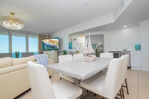A modern living room with a dining area, a kitchen, and a large window. - Chic Three Bedroom Condo with Beautiful Gulf Views! Complimentary Boat Slip! (Orange Beach)