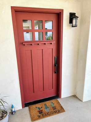 A red door with a window, a doorbell, and a welcome mat. - Comfy guest house with AC in sunny North Hollywood! (Los Angeles)