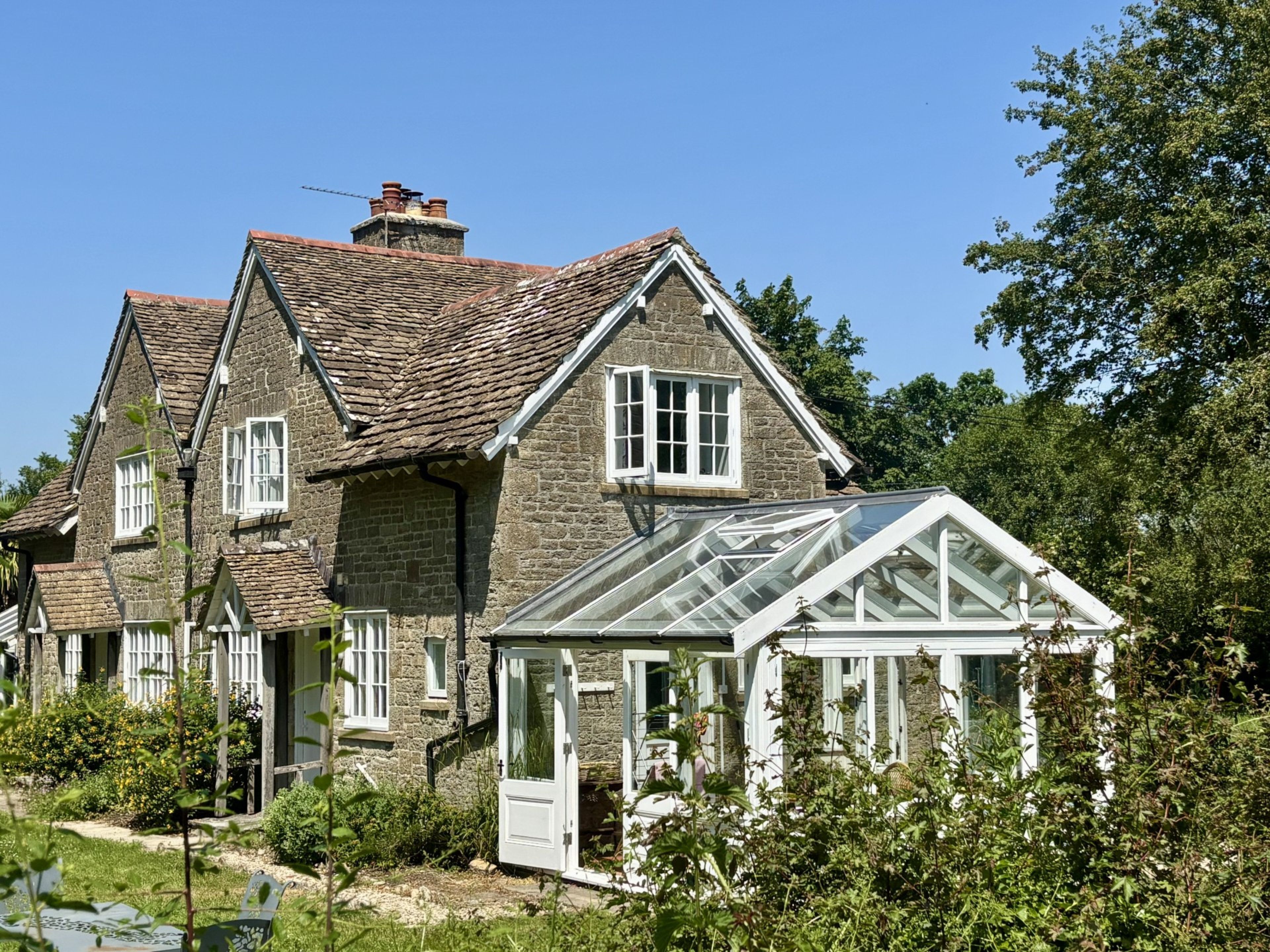 A stone house with a glass conservatory.