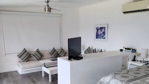 A modern hotel room with a sofa, a flat-screen TV, a desk, a bed, and a ceiling fan. - Comfortable House with excellent view Acapulco (Acapulco de Juárez)