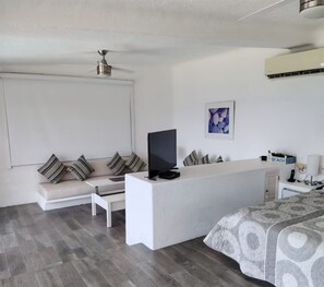 A modern hotel room with a sofa, a flat-screen TV, a desk, a bed, and a ceiling fan. - Comfortable House with excellent view Acapulco (Acapulco de Juárez)