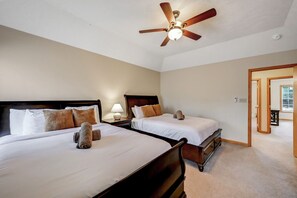 A hotel room with two beds, a ceiling fan, a nightstand with a lamp, and a door leading to another room. - Ski/family/kids/fully-stocked kitchen/spacious (Coolbaugh Township)