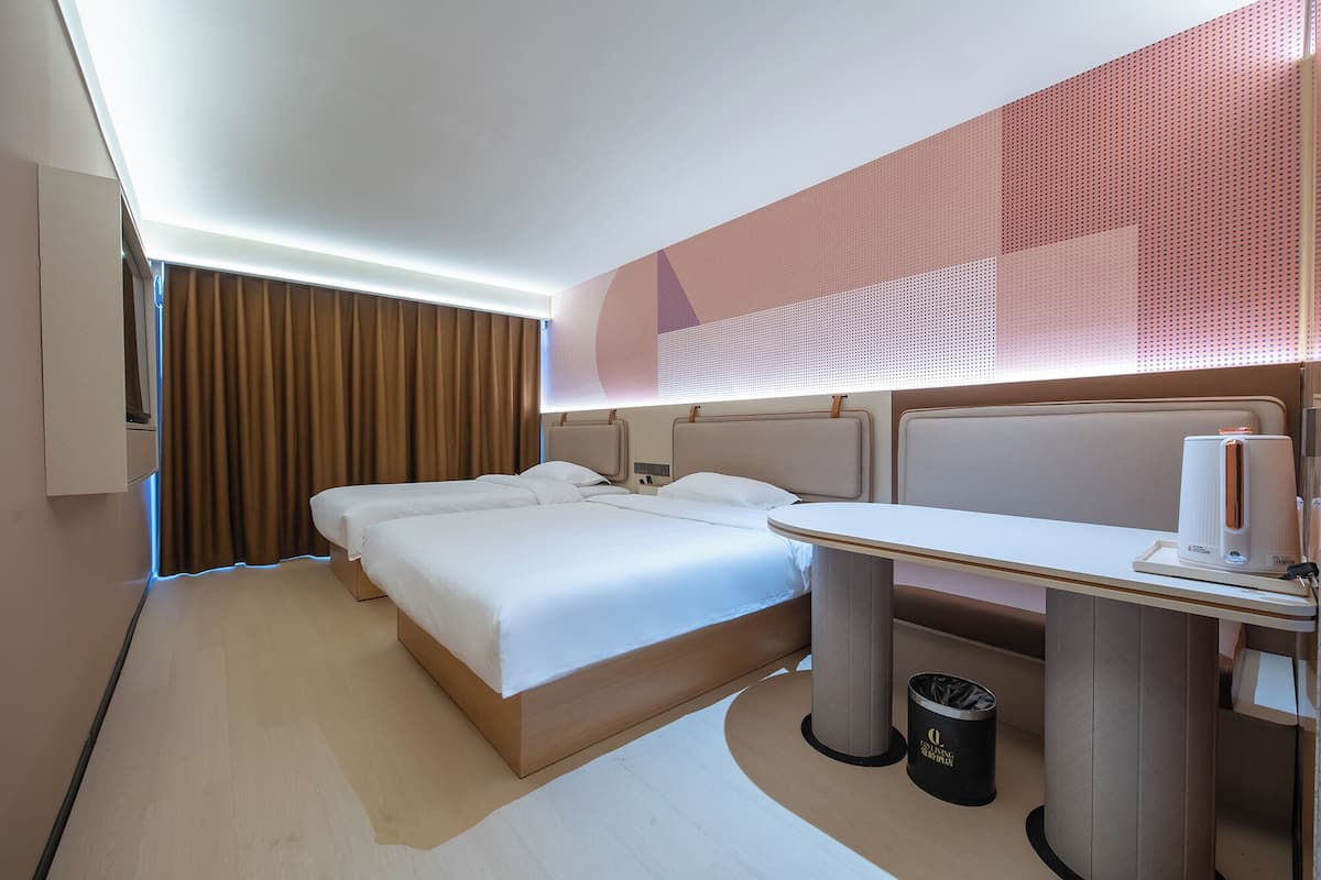 Moderni hotellihuone, jossa on suuri sänky, työpöytä ja roskakori.