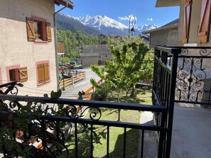 A balcony with a view of snow-capped mountains, a parked motorcycle, and a small tree. - L'IMPERIAL - VAL CENIS (VAL CENIS)
