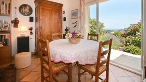 A dining area with a table, chairs, a cabinet, and a view through a glass door. - Villa vue mer au calme (SAN GIULIANO)
