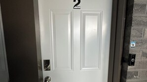 Une porte blanche avec le numéro « 2 » affiché, un clavier pour ouvrir la porte et un petit panneau sur le mur, à droite.