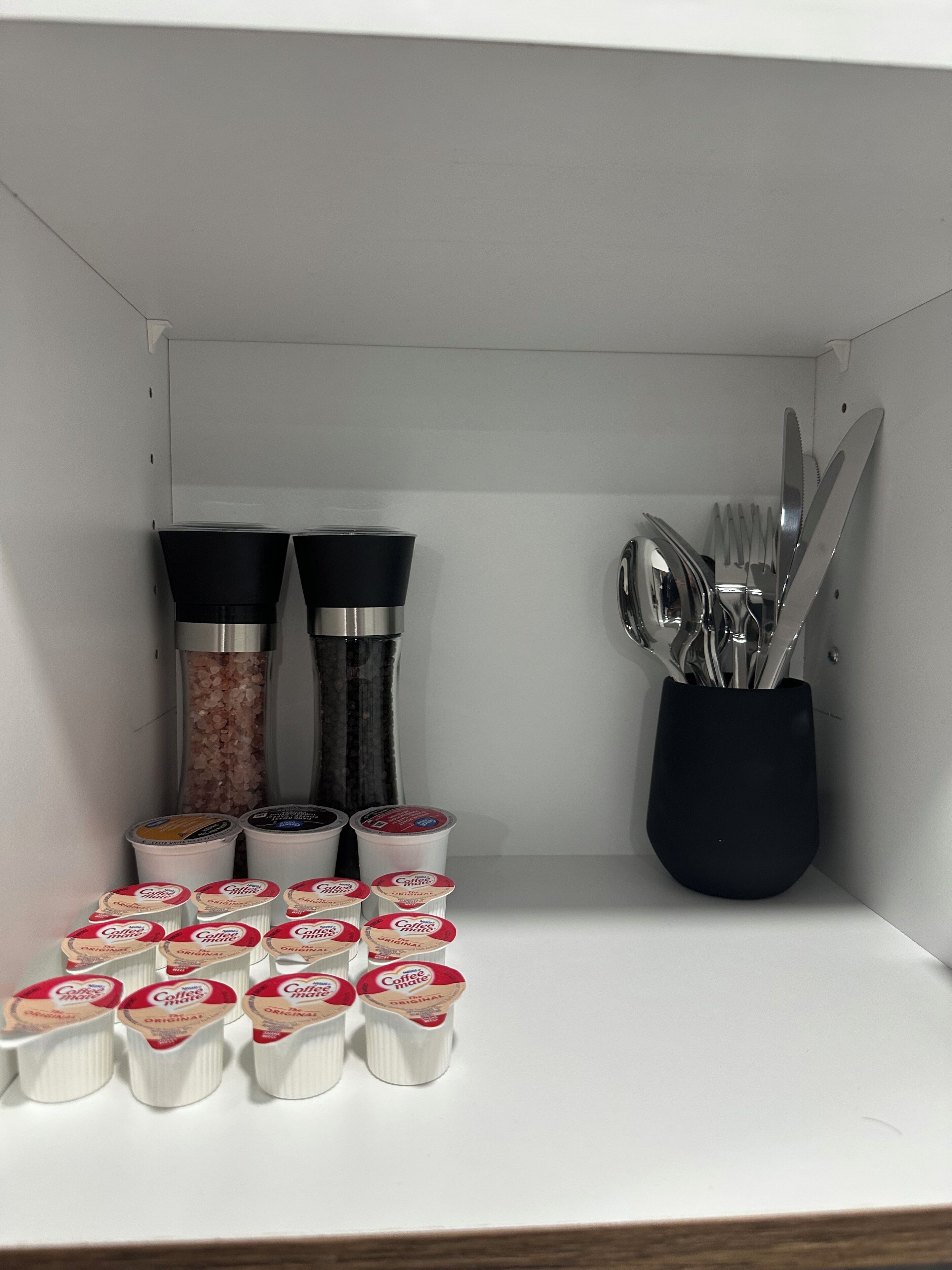 Ett kök med en kaffemaskin, salt- och pepparkar samt ett ställ för köksredskap.