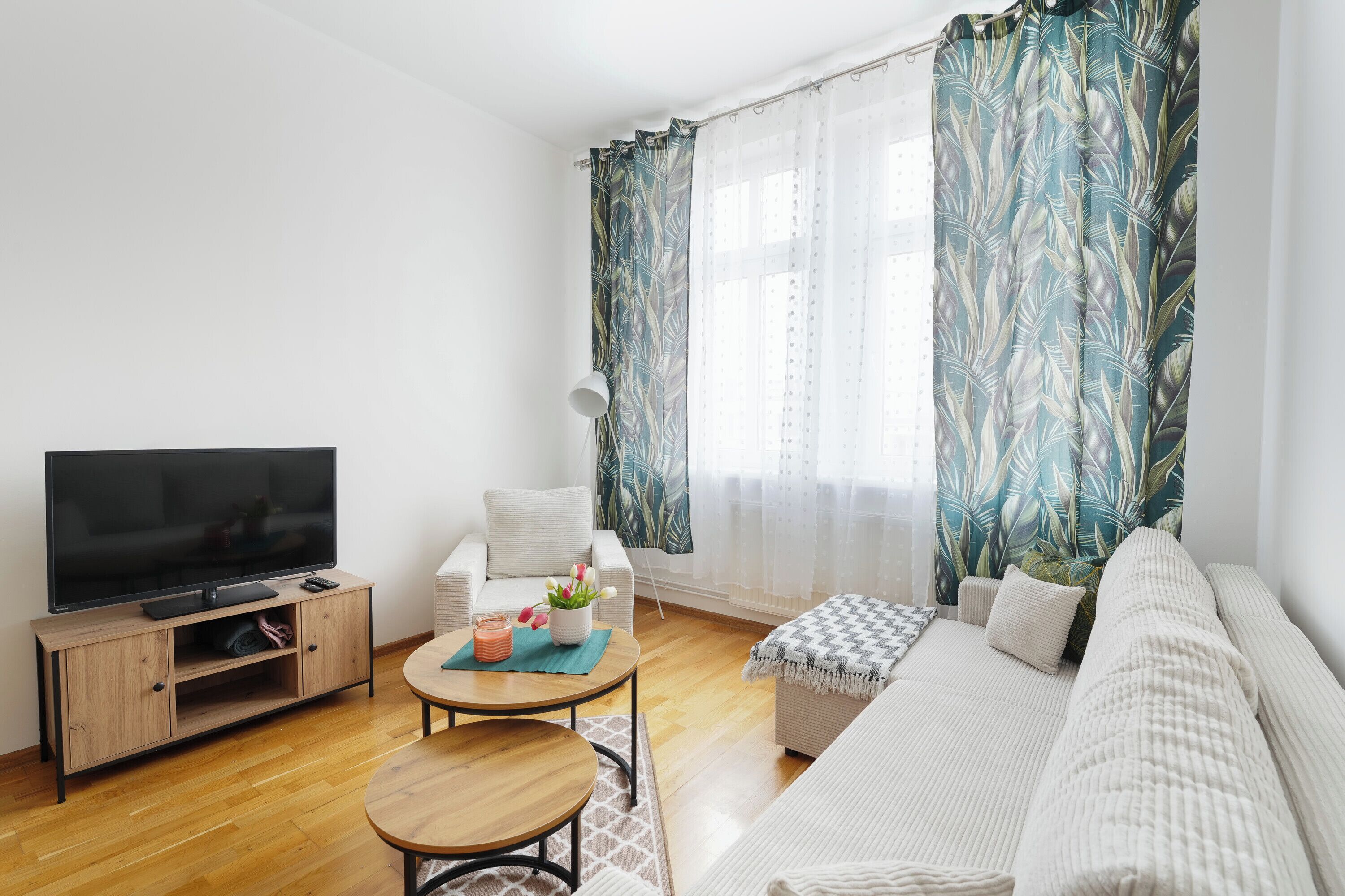A living room with a TV, sofa, coffee table, and curtains.