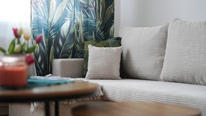 Een woonkamer met een bank, kussens, een tafel en een plant.