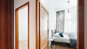 Een slaapkamer met een bed, nachtkastjes, een raam met gordijnen en een deur.