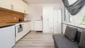 Kompakti keittiö, jossa on valkoiset kaapit, puinen työtaso ja sisäänrakennettu uuni.