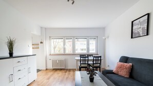 Moderni olohuone, jossa on sohva, ruokapöytä, tuolit, patteri ja ikkuna, josta on näkymä.