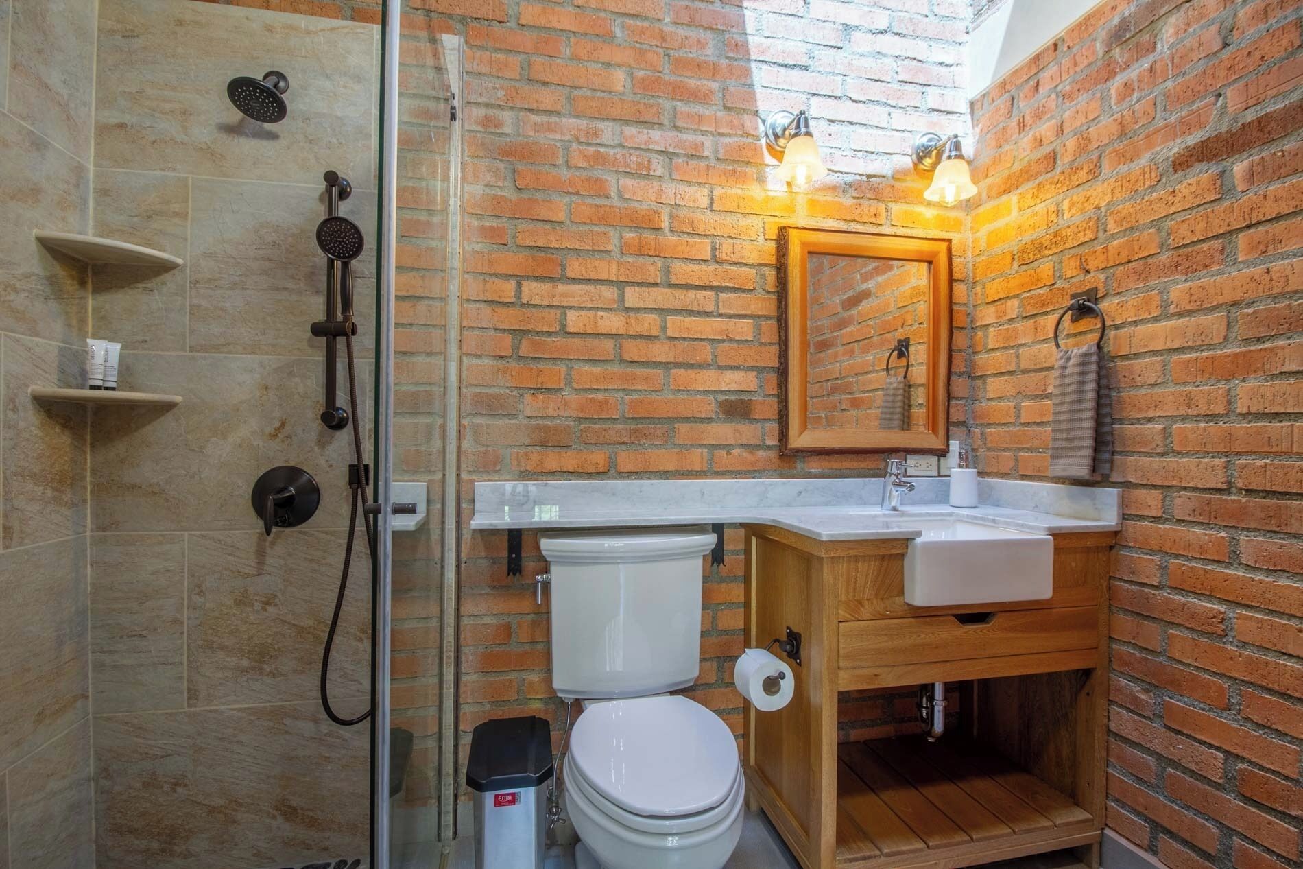 Un baño con ducha, inodoro, lavamanos y espejo.