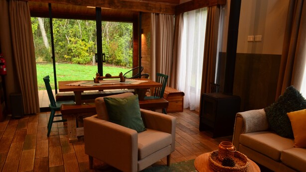 Un salon chaleureux avec un plancher en bois, un canapé, un fauteuil, une table et une cheminée.