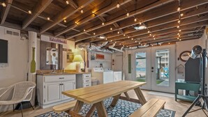 A kitchen with a wooden table, white cabinets, and a hanging light fixture.