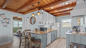 A kitchen with wooden beams, a central island, and a view to the outside.