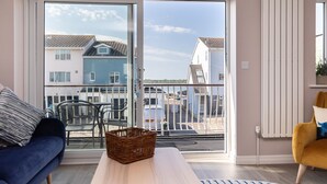 A living room with a sofa, a table, and a chair. - Modern town house situated in a quiet location with views across the harbour (Christchurch)