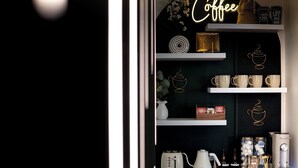 Une présentation sur le thème du café, avec un panneau néon, des étagères remplies de tasses à café, une machine à café et une bouilloire à thé.